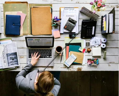 femme assise devant son ordinateur portable avec plein de document administratif à gérer